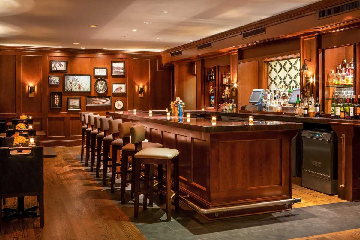 A welcoming bar counter with stools, shelves lined with bottles, and framed artwork on the walls. The atmosphere is cozy, inviting, and perfect for social gatherings or enjoying a quiet drink after a day of exploration.