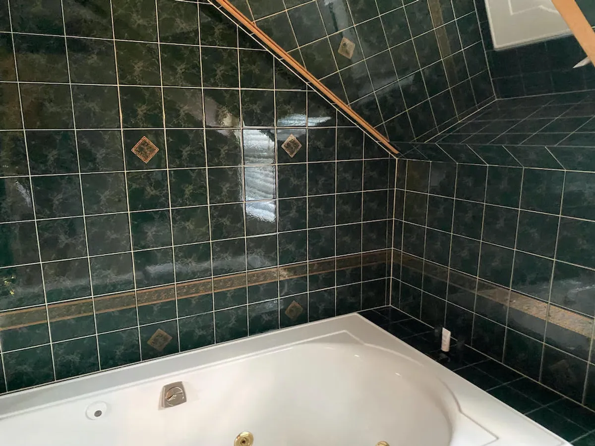 A modern bathroom with a luxurious jacuzzi tub, green tiled walls, and elegant decorative tiles. The ambiance is spa-like, invoking tranquility and relaxation after an active day, and exemplifies the 'multiple modern bathrooms' feature.